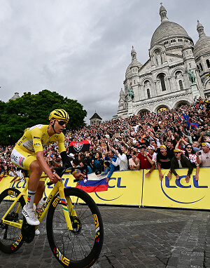 Cycliste en maillot jaune passant devant le Sacré-Cœur sous les acclamations du public lors du Tour de France